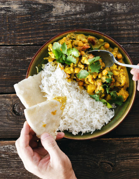 istock Man eats cauliflower spicy curry with rice and naan bread 1031868172