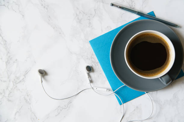 istock Workplace flatlay with coffee cup, papers and earphones on marble table 1031876580