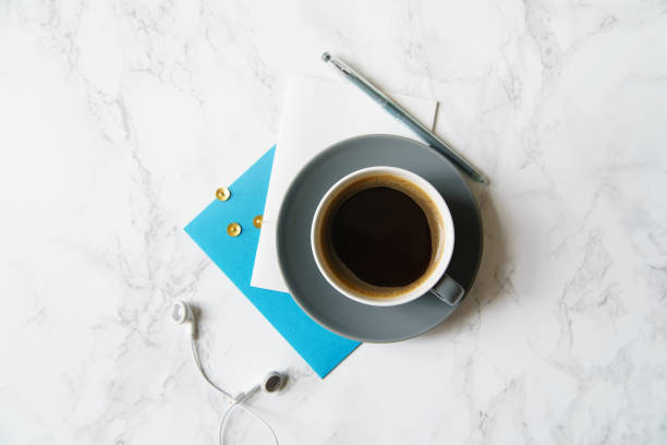 istock Workplace flatlay with coffee cup, papers and earphones on marble table 1031876618