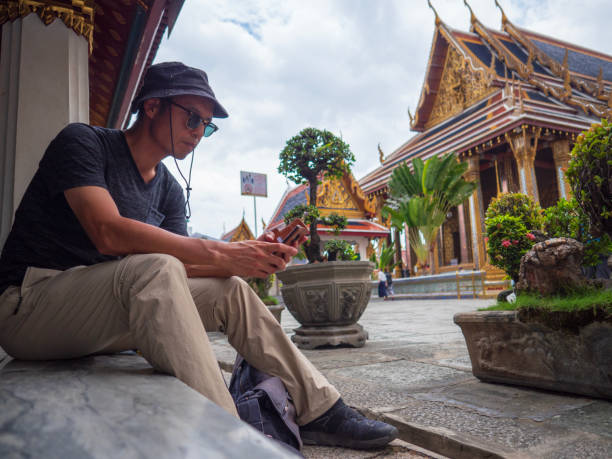 tourist mit smartphone in buddhistischen tempel - bangkok thailand asia temple stock-fotos und bilder