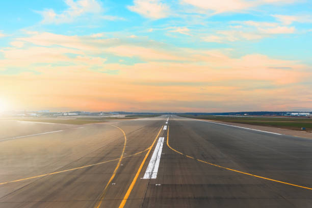 pista dell'aeroporto dopo l'orizzonte del tramonto e pittoresche nuvole di cirro nel cielo. - runway airport airfield asphalt foto e immagini stock