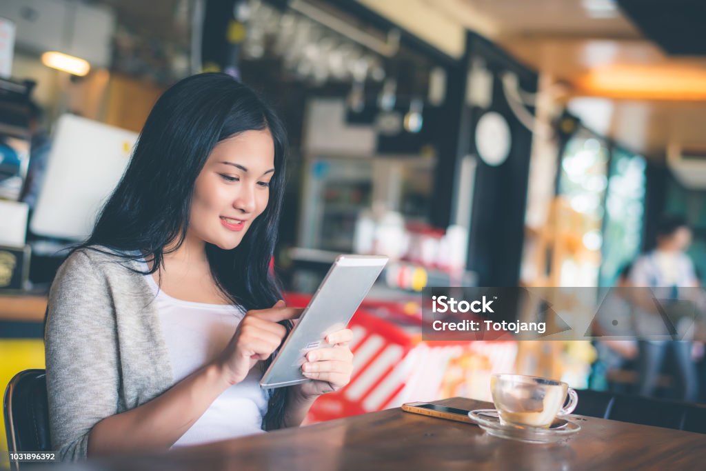 Schöne attraktive junge Asiatin mit Smartphone oder Handy im Café oder Kaffee Shop am Morgen - Lizenzfrei Asien Stock-Foto