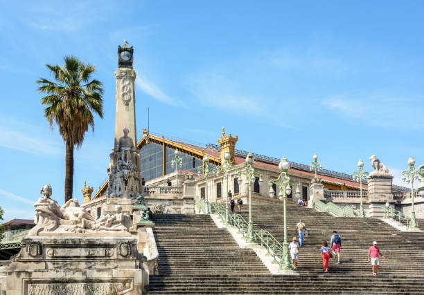 The monumental staircase of Saint-Charles train station in Marseille, France, with its 104 steps, pylons, statues, sculpted groups and Art Deco street lights seen from downstairs. Marseille, France - May 20, 2018: The monumental staircase of Saint-Charles train station, built in 1925, counts 104 steps, is 15,5 meters high and decorated by several sculpted groups. marseille station stock pictures, royalty-free photos & images