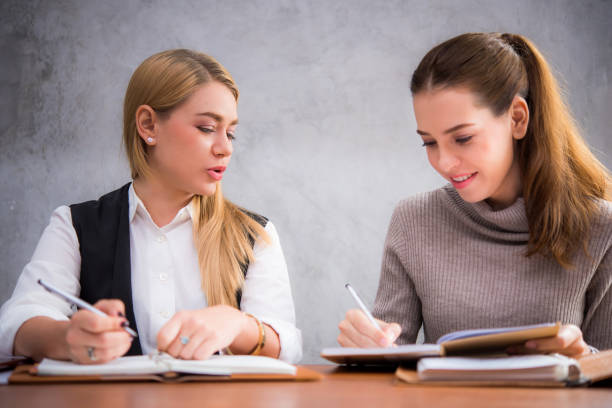 istock Two young attractive women studying together at a library 1031910060