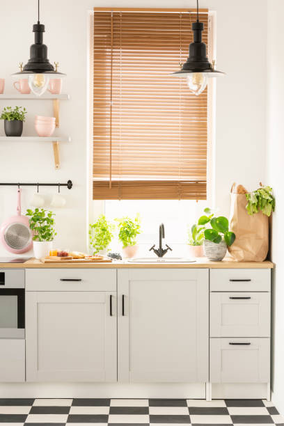 istock Lamps above wooden countertop with plants in bright kitchen inte 1031913192