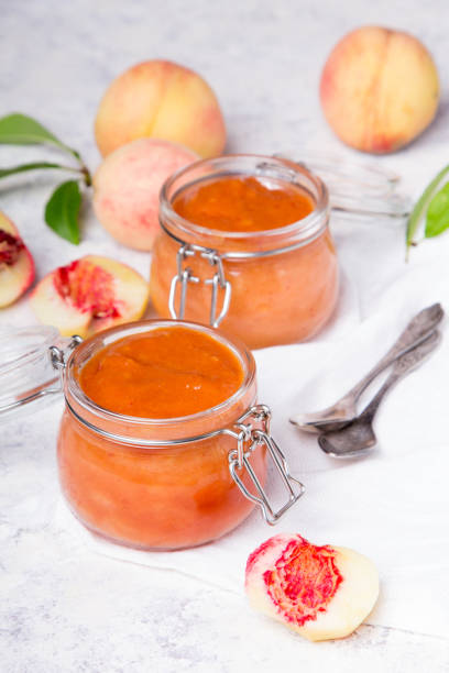 домашнее персиковое варенье с органическими фруктами. сладкие консервы н�а светлом фоне - preserves jar apricot marmalade стоковые фото и изображения