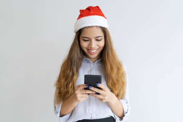 istock Smiling woman using smartphone and wearing Santa Claus hat 1031940356