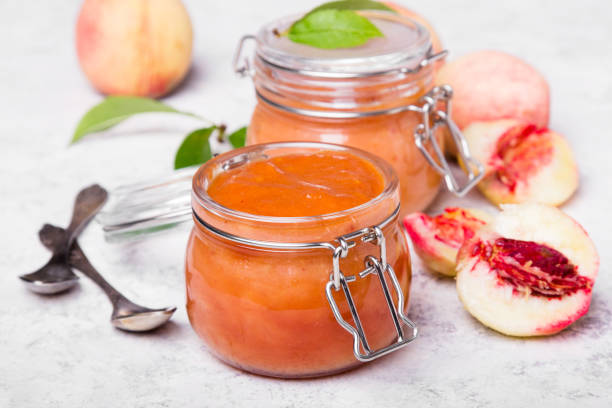 домашнее персиковое варенье с органическими фруктами. сладкие консервы на светлом фоне - preserves jar apricot marmalade стоковые фото и изображения