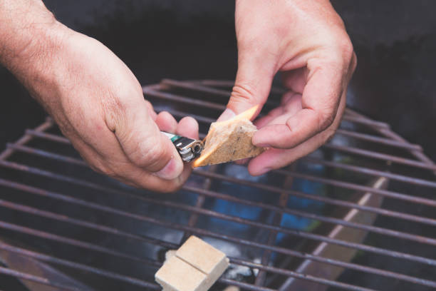 Close up of man setting fire for barbecue grill.