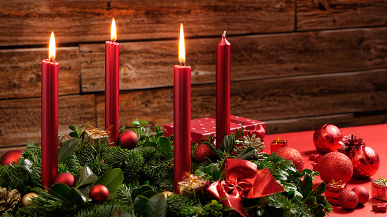 Advent wreath with three burning candles and festive decoration in front of a vintage wooden wall, studio shot with selective focus, copy space, no persons