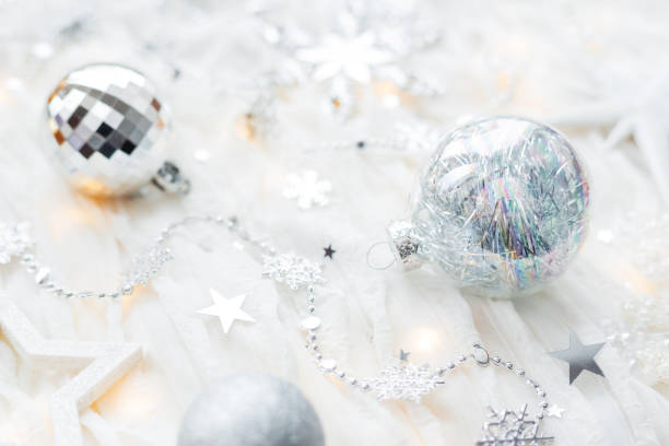 istock Christmas and New Year holiday background with decorations and light bulbs. Silver and white shining balls, snowflakes and star confetti. 1031955974