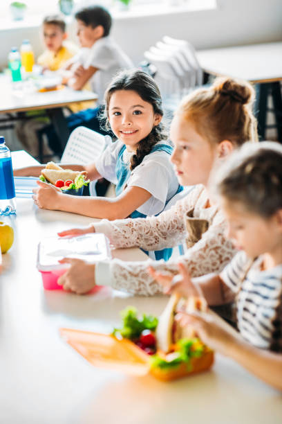 małe szczęśliwe uczennice biorące obiad w szkolnej stołówce - school lunch lunch child healthy eating zdjęcia i obrazy z banku zdjęć