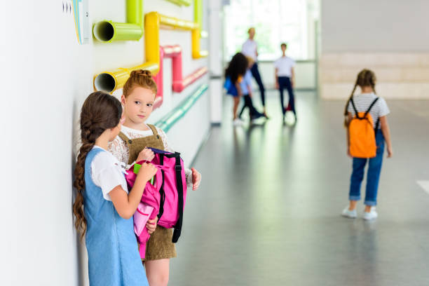 istock two adorable schoolgirls chatting at school corridor during break 1031956222