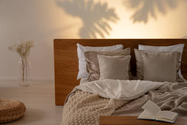 istock Pillows on a bed with a headrest and leaf shaped shadows on the wall in the background in the bedroom interior. Real photo 1031968576