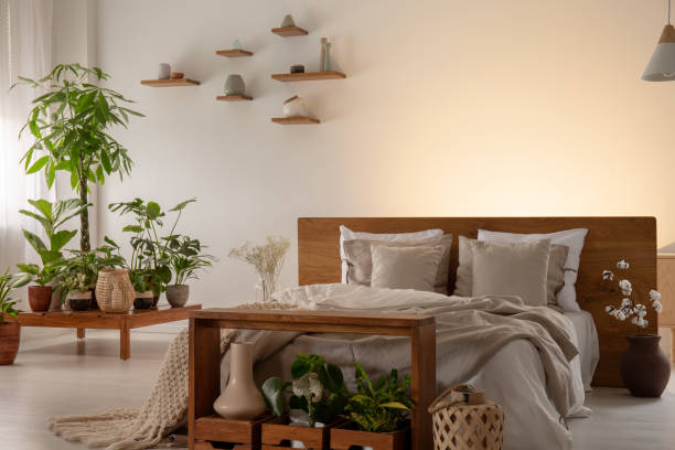 istock Plants in a modern bedroom interior with a comfy bed decorated with pillows and empty wall in the background. Place your graphic 1031968618