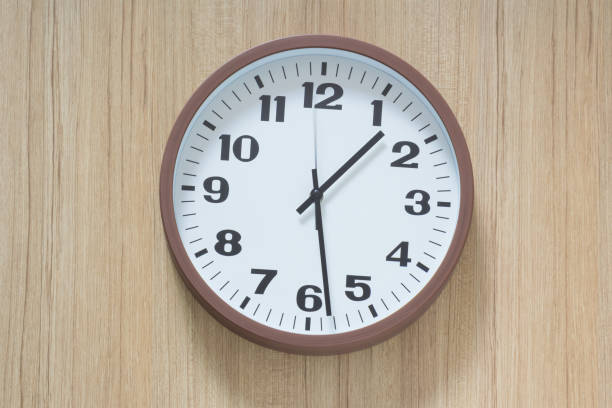istock brown and white plastic clock hangs on wooden wall 1031975020