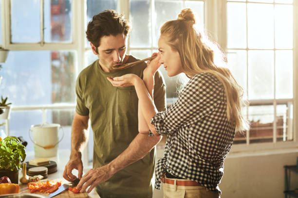 I added a special ingredient Shot of a young couple preparing a meal together at home preparing food stock pictures, royalty-free photos & images
