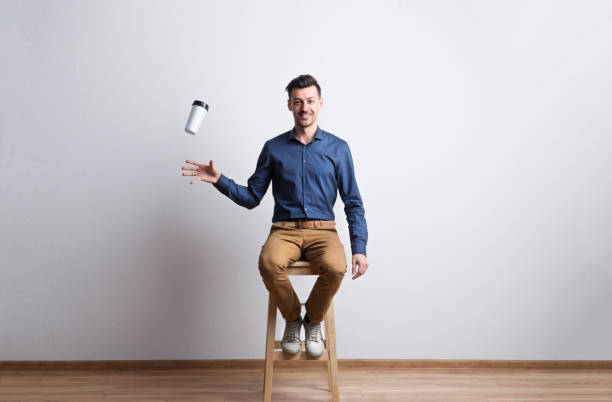 jeune homme avec une tasse de café dans un studio, assis sur un tabouret. - male mug shot cut out one person photos et images de collection