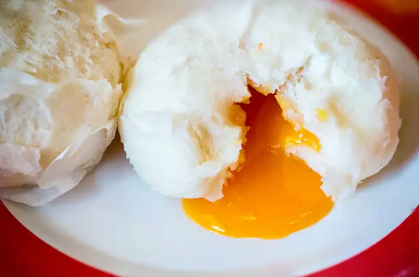 Photo of Chinese steamed bun and orange sweet creamy lava on chinese pattern dish. Dimsum Chinese famous food.