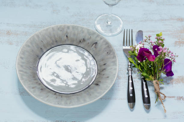 istock Rustic table setting with purple flowers and empty wine glass on light wooden table. 1032012654