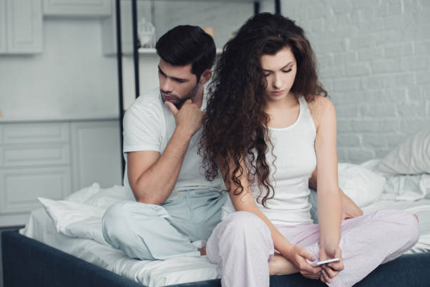 istock young woman using smartphone while upset man sitting behind on bed, relationship difficulties concept 1032026486