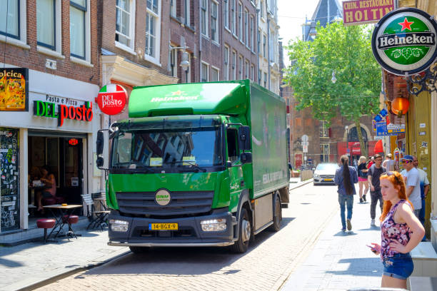 Heineken beer electric delivery truck bringing beer to bars in the narrow streets of the city center in Amsterdam Heineken beer electric delivery truck bringing beer to bars in the narrow streets of the city center in Amsterdam, the Netherlands. People are walking on the sidewalk. wellen stock pictures, royalty-free photos & images
