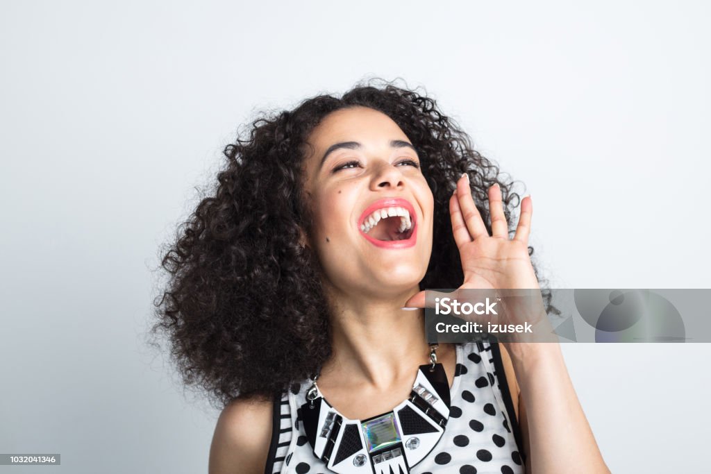 Excited young woman shouting Close up of beautiful young woman with curly hair shouting on white background 20-24 Years Stock Photo