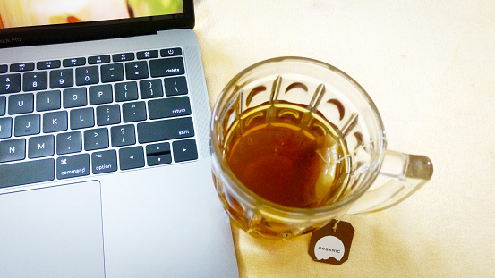 Organic India Green Tea in Glass Mug Honey & Tulsi with MacBook Pro Laptop on side
