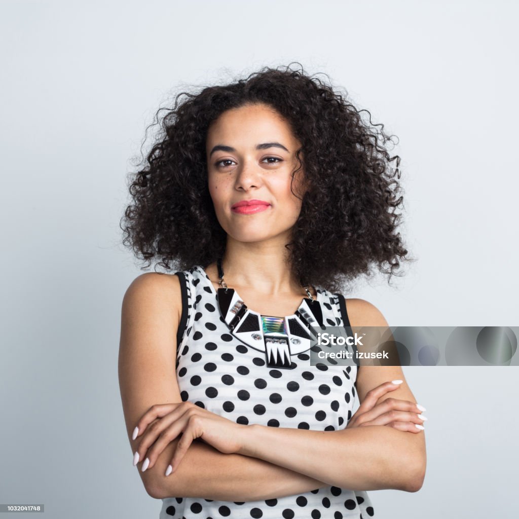 Portrait of stylish young woman Portrait of stylish young woman with curly hair with arm crossed on white background 20-24 Years Stock Photo
