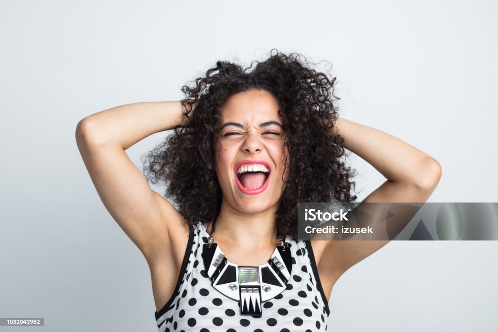 Attractive woman feeling excited Close up portrait of young attractive woman feeling excited on white background. Female with hands in hair shouting in joy. Close-up Stock Photo