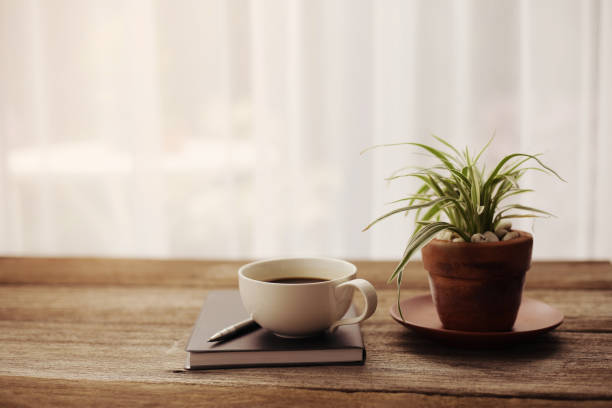 istock Coffee cup and black notebook with pen and plants on wooden table 1032044556