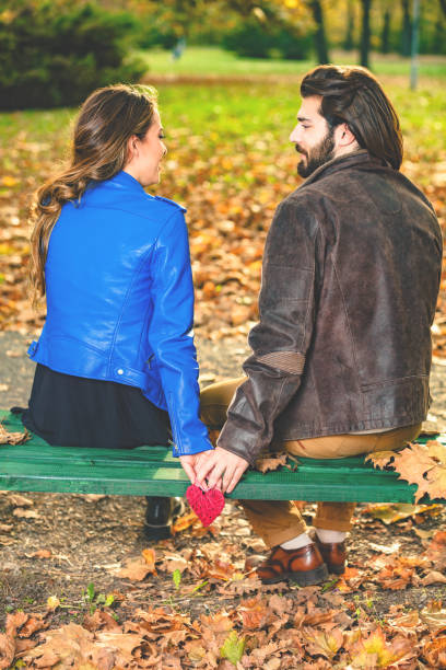 istock Couple holding heart-shape on a bench in the park. 1032054126