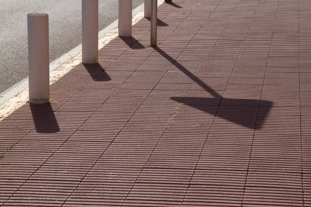 Diagonal shadow of a signpost over the sidewalk
