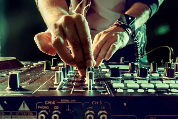 Photo of DJ playing music at mixer closeup