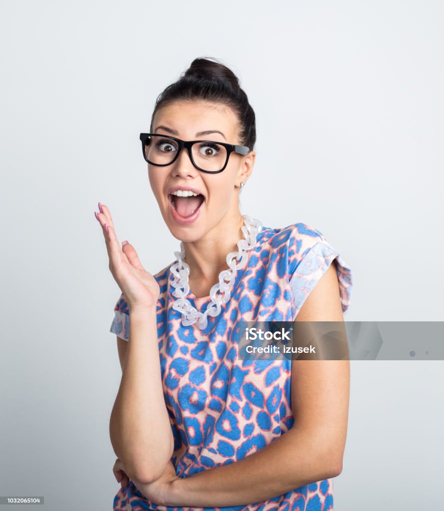Energetic young woman in eyeglasses Portrait of Energetic young woman wearing eyeglasses standing against white background with surprised expression. Surprise Stock Photo