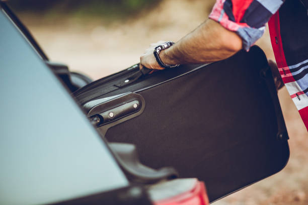 istock Man packing suitcase in a car 1032069688