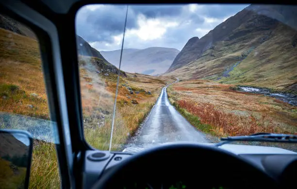 View out of Land Rover Defender 110 in Scottish Highlands, on the road in Glen Etive. It's early in the morning and it's cloudy.