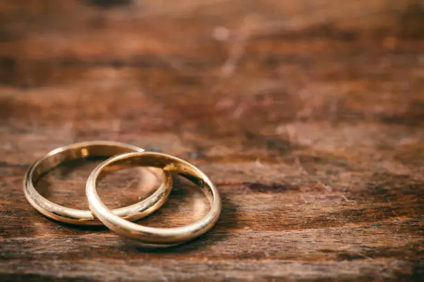 A pair of golden wedding rings on wooden background, copy space