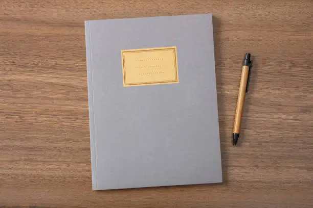 Photo of Grey school notebook or diary, old fashioned, on wooden desk, blank label, space for text, top view