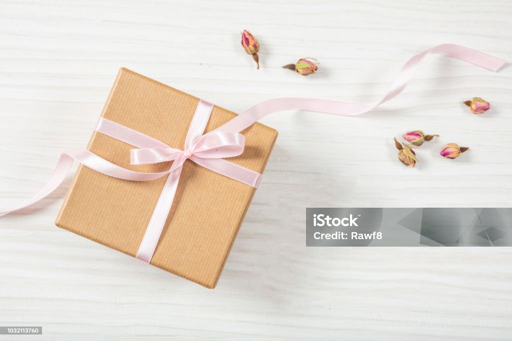 Hautnah und Draufsicht Beige Handwerk Geschenkbox mit rosa seidig Band auf einem hölzernen Hintergrund, Textfreiraum. - Lizenzfrei Band Stock-Foto