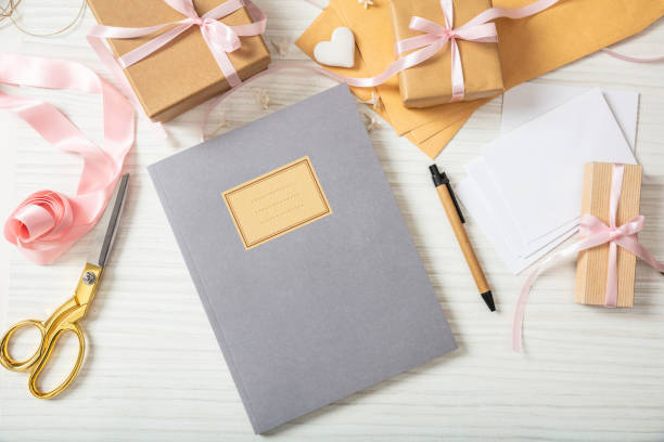 istock Flat lay and top view of notebook and invitations on a white wooden tabletop, blank space. 1032114538