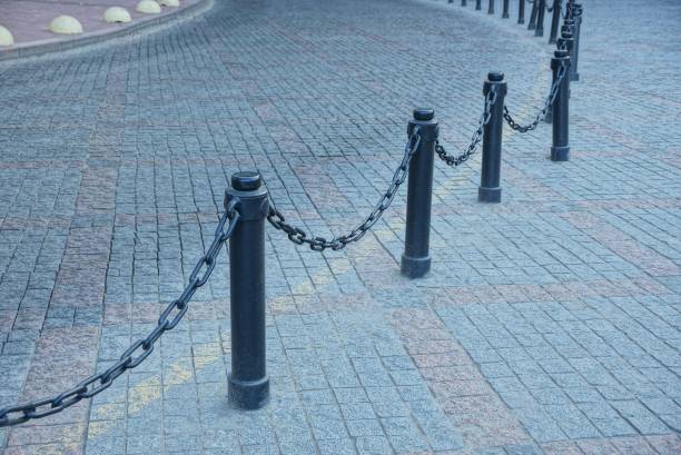 istock Black railing from iron chains and pillars on a gray pavement of stones 1032132750