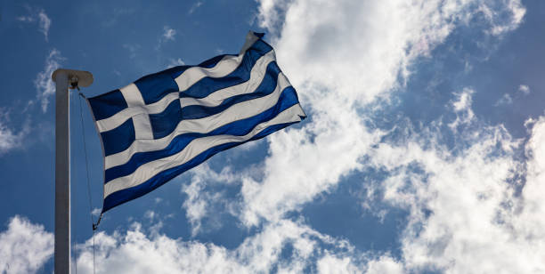istock Greek flag on flagpole waving on blue sky background 1032154330