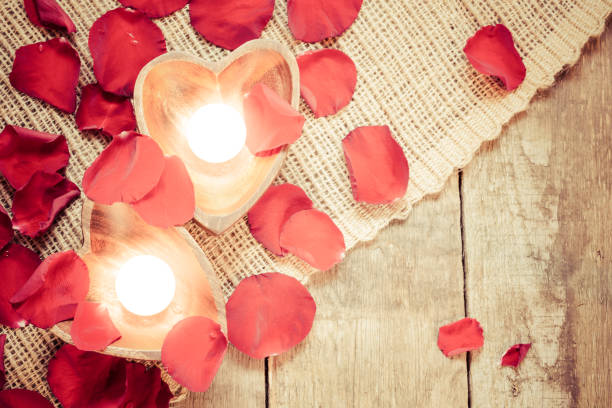 istock Two enlightened candles in heart-shaped candleholders with rose petals 1032154740