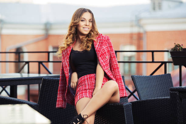 Young fashion woman in red tweed jacket and shorts suit at sidewalk cafe stock photo