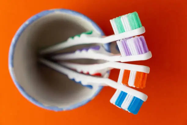 Color toothbrushes in glass, orange background, top view