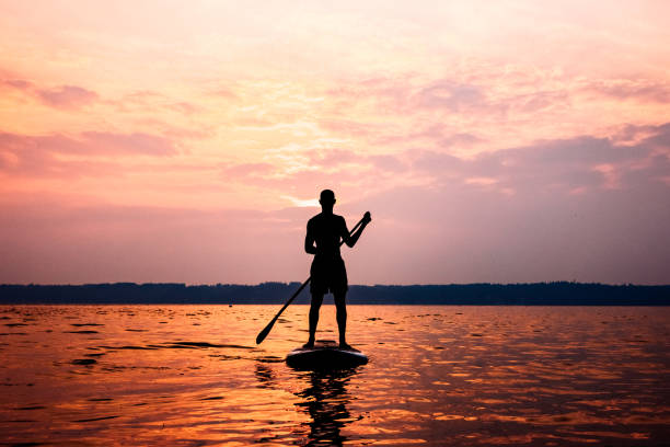 Young Adult Man Paddleboarding Puget Sound in Summer A young adult man floats on his standup paddleboard in the salt water of the Puget Sound, an inlet of the Pacific Ocean in Washington state, in the United States.  The sun casts pink and orange colors onto the water. tacoma photos stock pictures, royalty-free photos & images