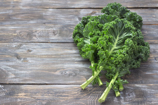 istock Fresh green curly kale leaves on a cutting board on a wooden table 1032168904