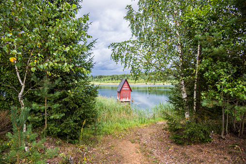 A small red wooden house near the lake and the forest, Latvia