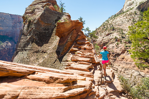 Young woman is walking along the ridge in beautiful scenery in Zion National Park along the Angel's Landing trail, Hiking in Zion Canyon, Utah, USA.